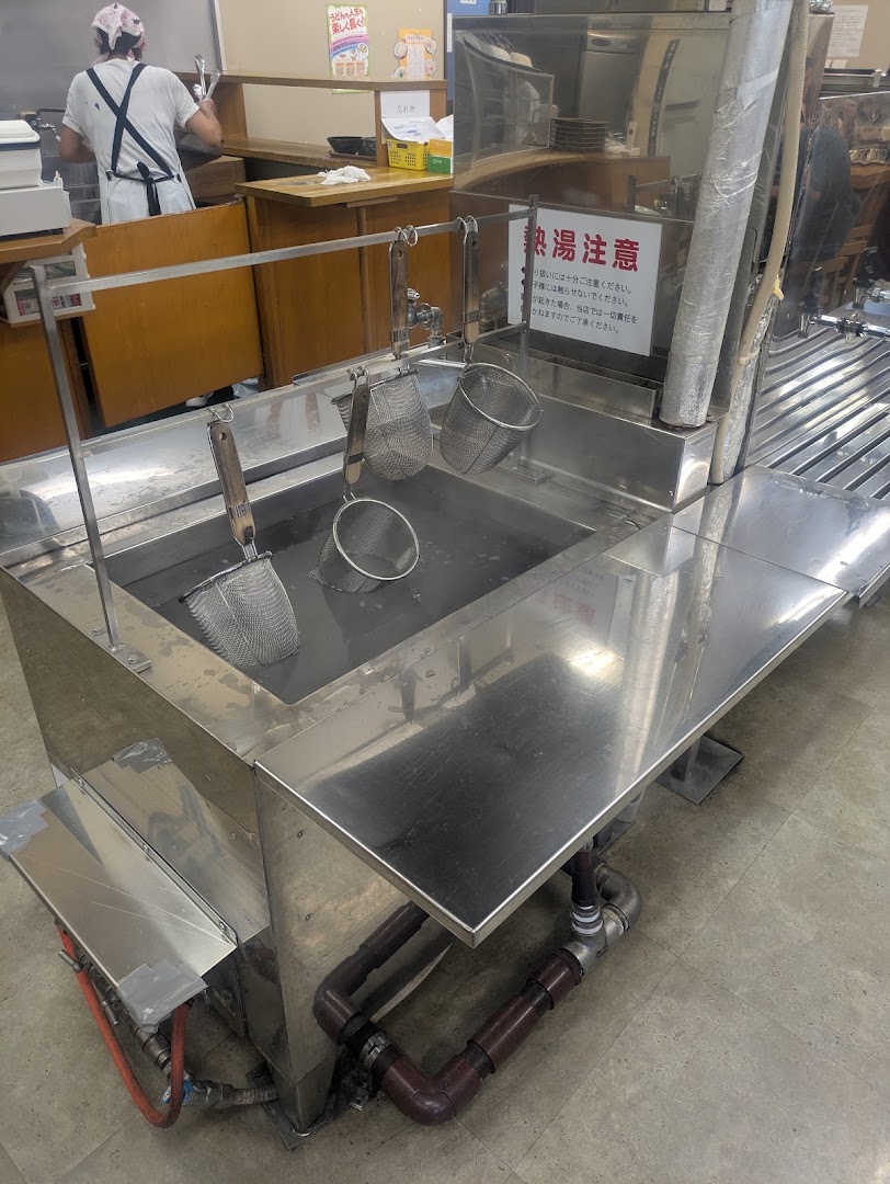 Wire noodle baskets at a full self-service udon counter in Takamatsu
