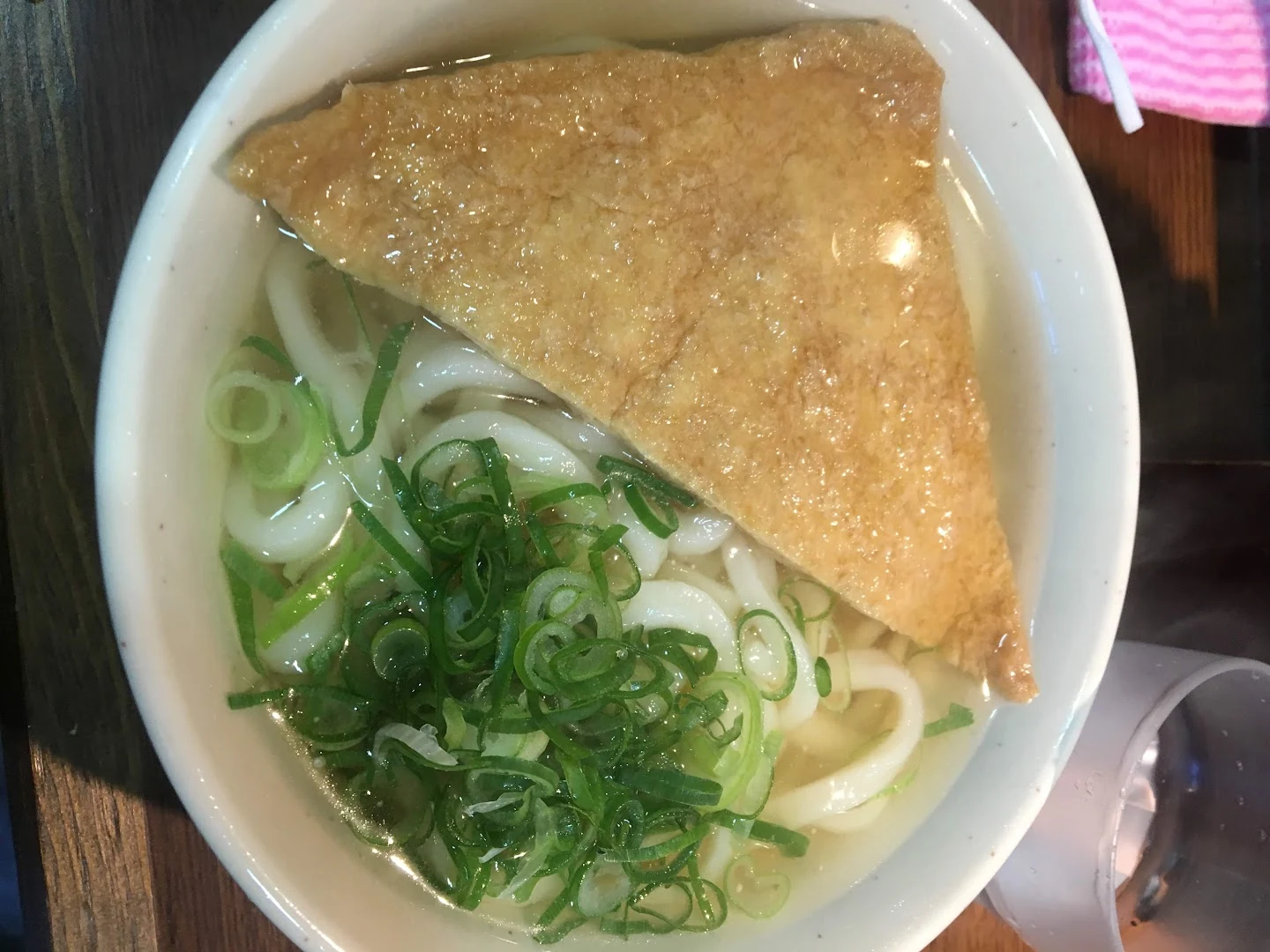 Kitsune udon topped with a large piece of fried tofu and green onions