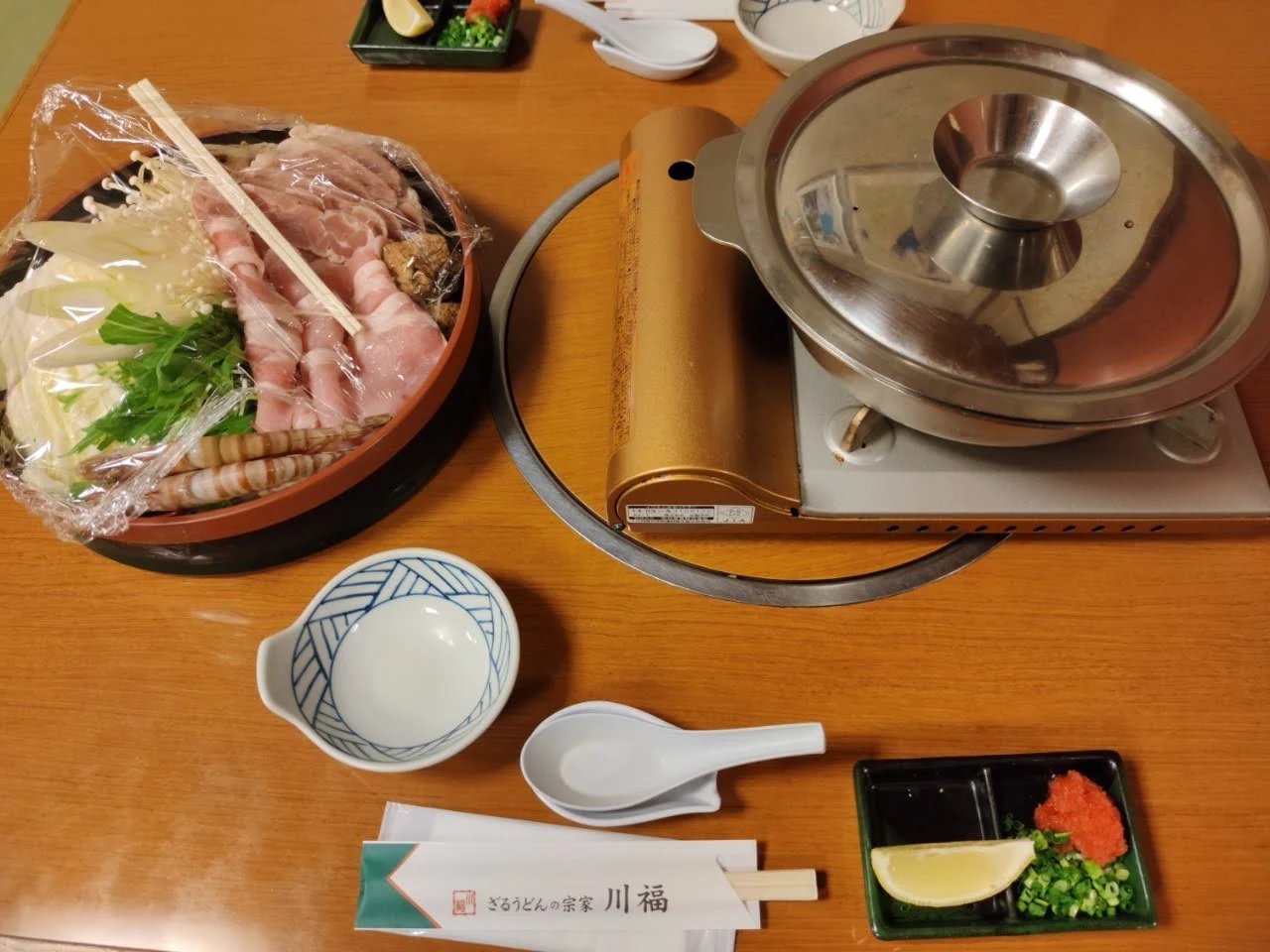 A tabletop nabe-suki hot pot with meat, vegetables and udon ingredients