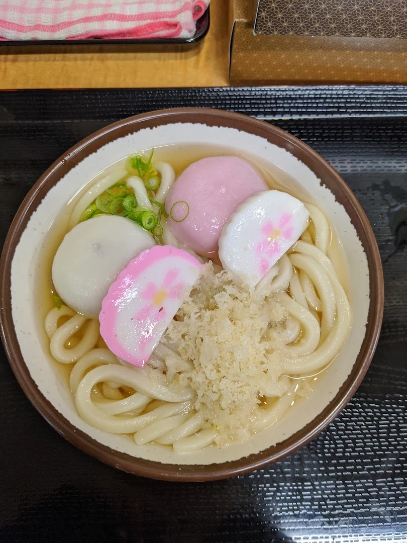 New Year udon topped with red-and-white fish cake and tempura crumbs