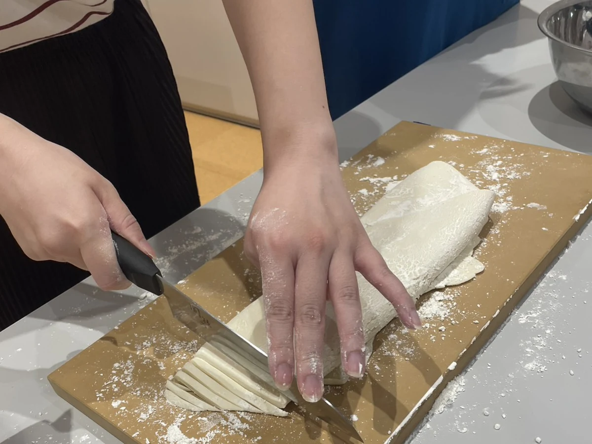 Close-up of fresh udon noodles being cut